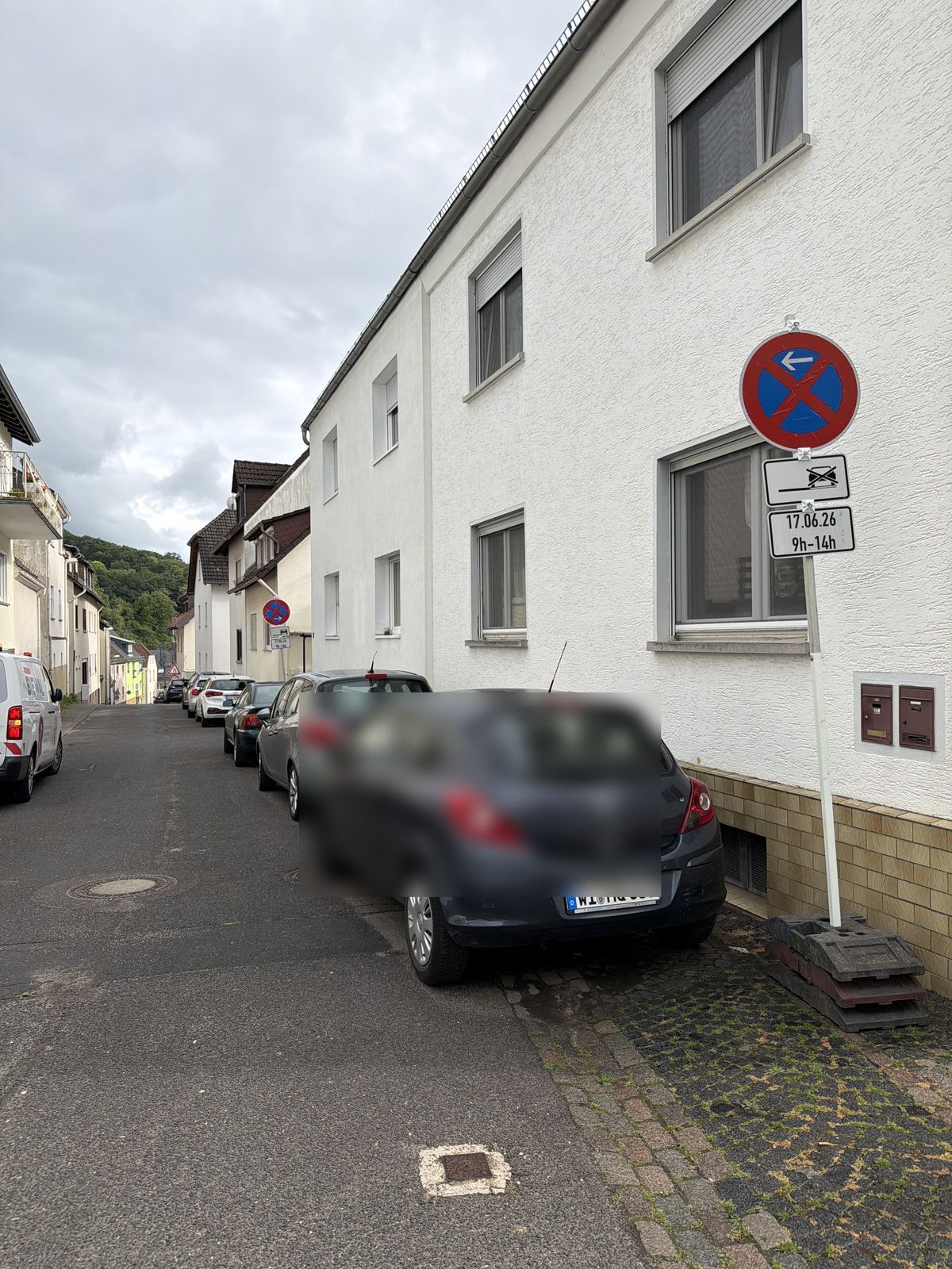 Halteverbotsschild an einer Wohnstraße mit parkenden Fahrzeugen